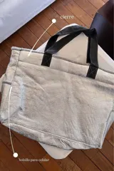 Bolso tote plateado con textura arrugada, doble asa corta negra, cierre superior y bolsillo lateral para celular.