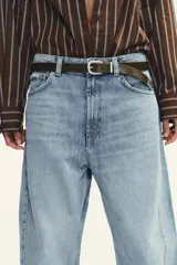 Pantalón de jean azul oscuro, tiro medio, corte amplio tipo baggy balloon con costuras torcidas y cinco bolsillos. Cierre frontal con cremallera y botón metálico.