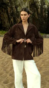 Blazer marrón de gamuza ligera con flecos largos en las mangas y botones de cuerno. Corte recto y bolsillos frontales.