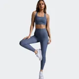 Calza de compresión de longitud completa, color azul grisáceo, con cintura de tiro alto acanalada y paneles laterales acanalados. Presenta un diseño en forma de V en la espalda y el logo 2XU en la cintura trasera.