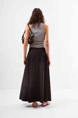 Falda larga de color negro, con cintura lisa y un amplio volado fruncido que comienza a la altura de la cadera, aportando volumen y movimiento.