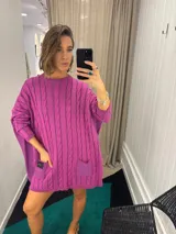Sweater negro de punto con diseño de trenzas, corte holgado, mangas largas y bolsillos frontales. Tejido artesanalmente en Uruguay, con puños altos ajustados.