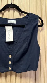 Chaleco azul marino de lino con corte sastrero y cierre frontal con botones dorados.