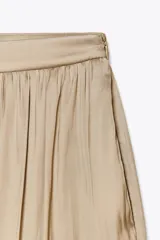Pantalón bombacho color beige de tiro alto, con elástico en la cintura y en los tobillos.