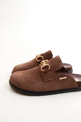 Mocasines tipo sueco de cuero gris con detalle de hebilla dorada.