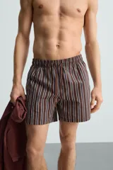 Bañador corto de hombre con estampado de rayas verticales en marrón, blanco y azul. Cuenta con cintura elástica ajustable con cordón, bolsillos laterales y trasero.