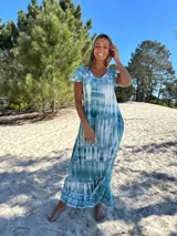 Vestido largo con estampado tie-dye en tonos celeste y blanco, con escote en V, mangas cortas con volados y corte holgado.