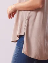 Camisa sin mangas color celeste, confeccionada en lino. Presenta cuello camisero, escote en V, abertura frontal con botones, dos bolsillos de parche en el pecho y terminación con botones en los laterales.