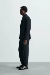 Pantalón de vestir gris oscuro, corte slim fit, confeccionado en tejido con 17% de lana. Cuenta con bolsillos frontales y traseros de vivo con botón. Cierre frontal con cremallera y botón.