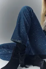 Pantalón de jean de tiro alto, denim azul rígido con lavado oscuro y apliques de brillos.