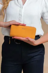 Billetera larga color beige de símil cuero, con cierre perimetral y bolsillo trasero con cierre.