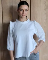 Blusa blanca de algodón con cuello con volados, mangas 3/4 con bordado calado y detalle de volados en los hombros.