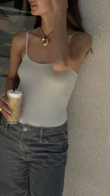 Collar con dije dorado irregular con agujero central, colgando de cordón negro ajustable.