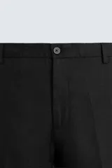 Pantalón negro de corte regular fit, confeccionado en tejido de lino. Presenta cintura con botón y cierre de cremallera, bolsillos frontales y bolsillos traseros de doble vivo.