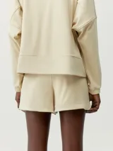 Short deportivo color beige, de tejido suave y elástico, con bolsillos laterales y cordón ajustable en la cintura.