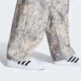 Pantalón cargo de corte ancho (baggy fit) con estampado de camuflaje de hojas en tonos beige, gris y blanco. Presenta bolsillos cargo en los laterales.
