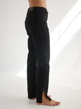 Pantalón negro de gabardina con alforzas verticales en los laterales y aberturas en los tobillos.