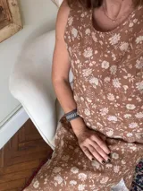 Vestido midi sin mangas, color marrón con estampado floral en blanco, con tajos laterales y cierre con botón en la espalda.