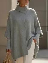 Capa o poncho tejido color verde esmeralda, con cuello polera alto que se cierra con un botón grande en el lateral. Presenta mangas cortas estilo japonesa y un calce amplio.