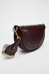 Bolso de hombro ovalado negro con asa de doble tira redonda con detalles metalizados dorados. Cierre imantado y asa de bandolera extraíble con tejido a contraste. Bolso interior con cierre mediante cremallera metálica.