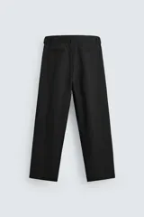 Pantalón negro de corte amplio con cinturón de tela con hebilla metálica. Presenta pliegues frontales, bolsillos laterales y traseros. Cierre frontal con cremallera y botón.