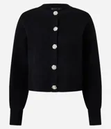 Cardigan negro de tricot con cuello redondo, mangas largas y cierre frontal con botones metálicos en forma de flor. El bajo es acanalado.