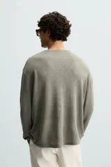 Jersey color verde claro de punto tejido en hilatura ligera de lino, corte relaxed fit, cuello redondo y manga larga con terminaciones en rib.