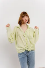 Camisa color crema de manga larga con cuello camisero y detalles de encaje en el escote. Se ata en la parte delantera.