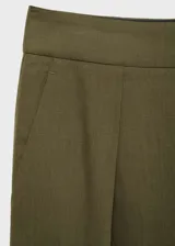 Pantalón de vestir verde oliva, de tiro medio y corte recto. Presenta cierre frontal oculto, bolsillos laterales y pinzas delanteras.