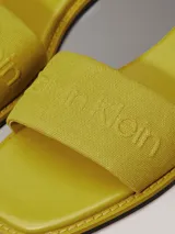 Ojotas amarillas de lona con logo de Calvin Klein grabado en la tira.