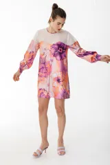 Vestido corto con vuelo de satén con maxi estampado floral combinado con organza semitransparente con líneas en el canesú. Tiene manga larga abullonada y lazo en la espalda para anudar.