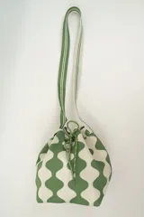 Bolso tipo bombonera tejido a crochet, con patrón geométrico en tonos rosa y marrón. Tiene cierre con cordón ajustable y correa de hombro.