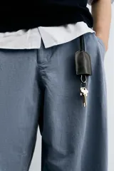 Pantalón de hombre color azul grisáceo, estilo balloon fit, confeccionado en mezcla de algodón y lino. Presenta pliegues en el delantero, cierre frontal con botón y cremallera, bolsillos laterales y bolsillos traseros de plastrón.