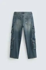 Pantalón de denim color beige, corte relaxed fit, con bolsillos laterales tipo cargo con solapa y cierre de botón. Cierre frontal con botón y cremallera.