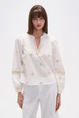 Blusa de algodón blanca con bordados geométricos en tonos dorados y grises. Presenta cuello mao, escote en V y mangas largas abullonadas con puños elásticos.