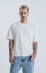 Remera blanca de algodón con corte crop, calce oversize, hombros caídos y cuello redondo.