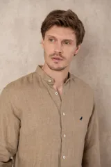 Camisa celeste de lino con cuello mao, corte slim fit, manga larga con puños abotonados y cierre frontal con botones.