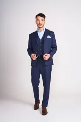 Traje de vestir azul marino a cuadros, compuesto por saco, chaleco y pantalón de vestir. El saco es de corte clásico con solapas de muesca, dos botones y bolsillo de pañuelo. El chaleco es cruzado con seis botones. El pantalón es de corte recto.