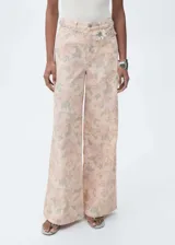 Pantalón de jean de corte wide leg con estampado floral en tonos pastel. Tiene tiro alto, cinco bolsillos, trabillas y cierre frontal con cremallera y botón.