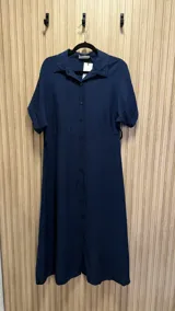 Vestido midi azul marino con cuello camisero, mangas cortas con dobladillo y abotonadura frontal completa.