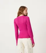 Blusa de punto fucsia con cuello redondo y manga larga abullonada. Tiene botones en forma de corazón en los puños y ondas en el bajo.