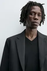 Blazer negro regular fit confeccionado en tejido de lana. Cuello con solapas de muesca y manga larga acabada en puño con botones. Bolsillos de vivo en pecho y de solapa en cadera. Detalle de bolsillo interior. Bajo con aberturas en espalda. Cierre frontal de botonadura.