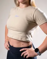 Remera corta color beige con logo estampado en el frente, de algodón elastizado y corte ajustado.