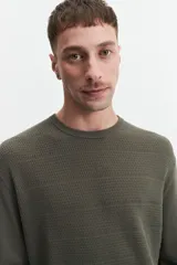 Buzo de punto color beige, con cuello redondo y mangas largas. Tejido con textura piquet y puños acanalados. Corte regular.