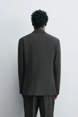 Blazer regular fit color gris oscuro con diseño de cuadros, confeccionada en tejido con lana. Tiene cuello con solapas de muesca, manga larga con puños abotonados, bolsillo de vivo en el pecho, bolsillos de solapa en la cadera, bolsillo interior, aberturas en la espalda y cierre frontal con botones.