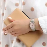 Reloj analógico Casio para mujer, con caja y correa de acero inoxidable plateado. Presenta una esfera redonda color rosa con textura guilloché, índices aplicados y visor de día y fecha a las 3.