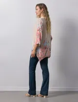 Blusa de gasa color beige con estampado floral en tonos rosa y celeste. Tiene cuello a la base, escote en V y abertura central con botones. Las mangas son 3/4 y regulables con presilla y botón.