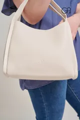 Bolso tipo tote color crema, con doble asa de hombro y logo de la marca grabado en el frente.
