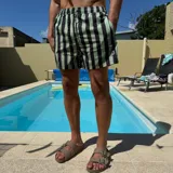 Short de baño negro con rayas verticales blancas, cintura elástica con cordón ajustable y logo de la marca en la pierna derecha.