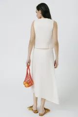 Top sin mangas de lino color crudo, con cartera asimétrica y botones de madera. Tiene ojales bordados con forma de frutillas.